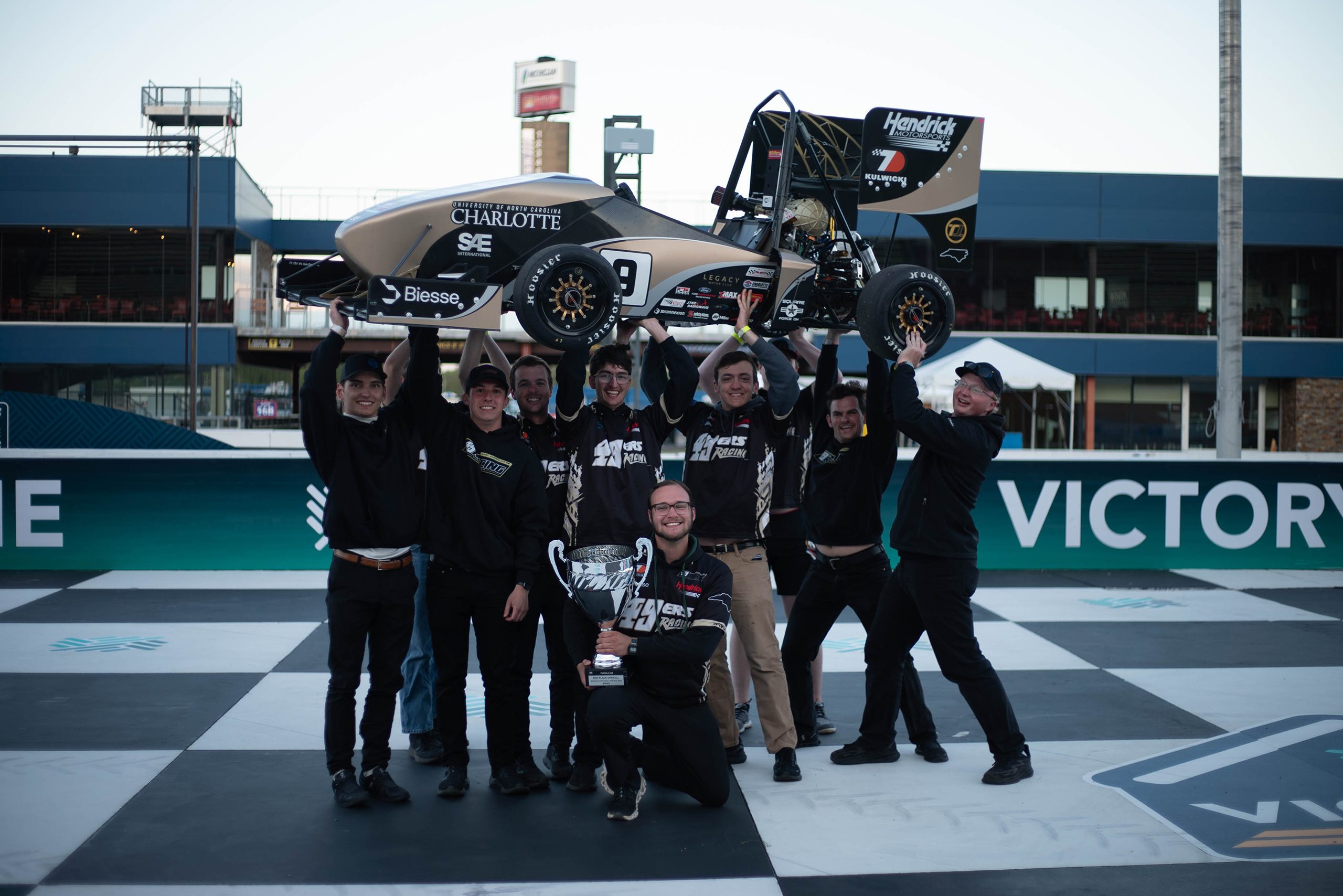 49ers Racing team members hoist race car in the air